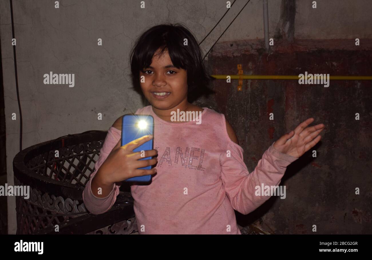 Une fille indienne qui clignote sur le mobile dans le balcon la nuit en appel par PM Narendra Modi pour montrer la solidarité avec la nation contre le virus Corona lutte Banque D'Images