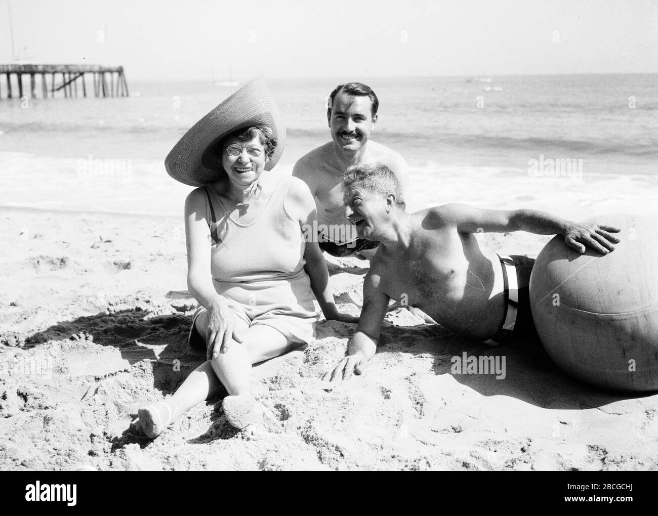 Le cinéaste américain de travelogue André de la Varre (1904 - 1987) se détend sur une plage à côté d'amis hommes et femmes, Californie, 1931. Photographie par Burton Holmes. Banque D'Images