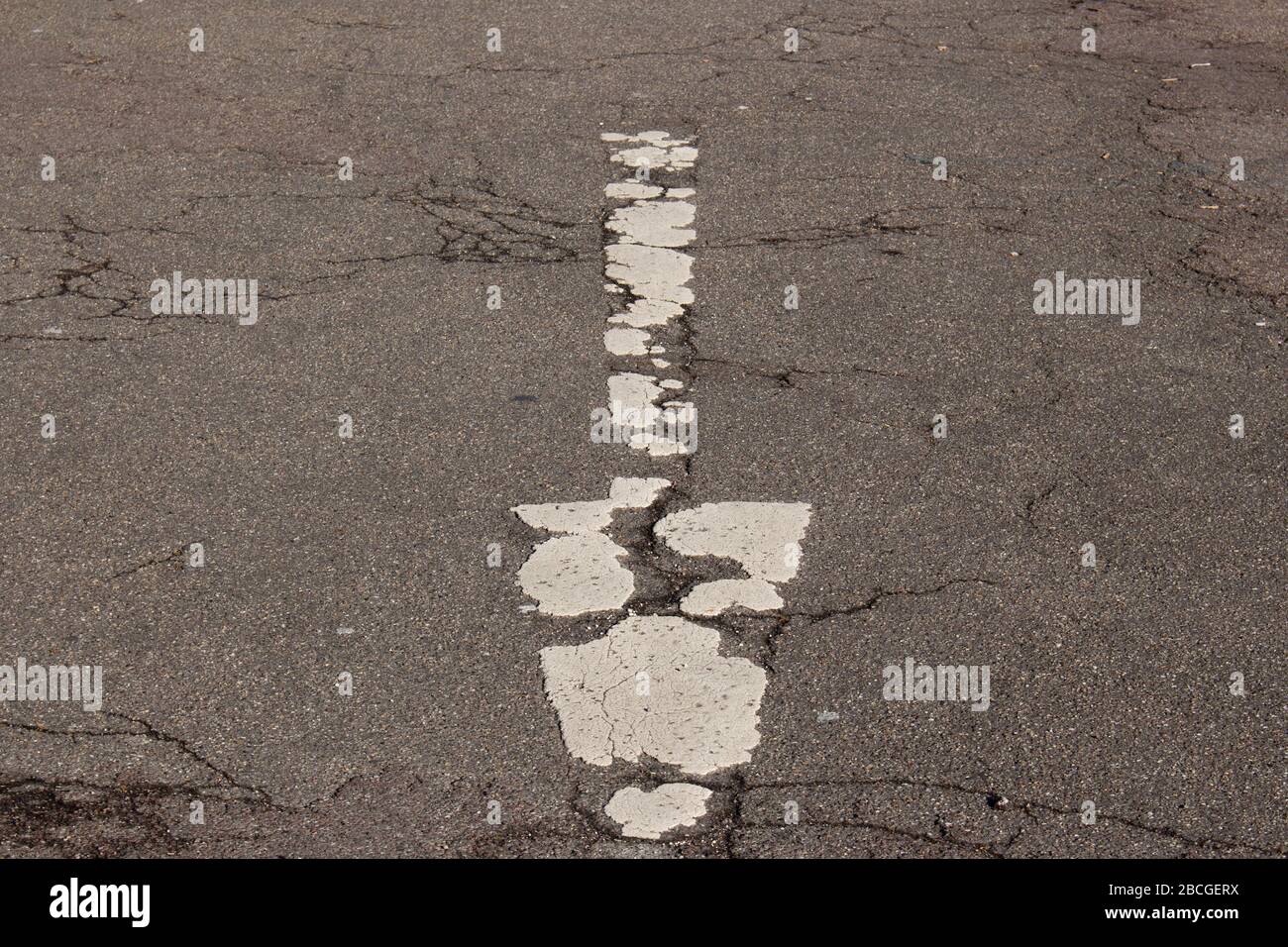 Flèche blanche vieille, sale et décoloration sur une ancienne route endommagée Banque D'Images