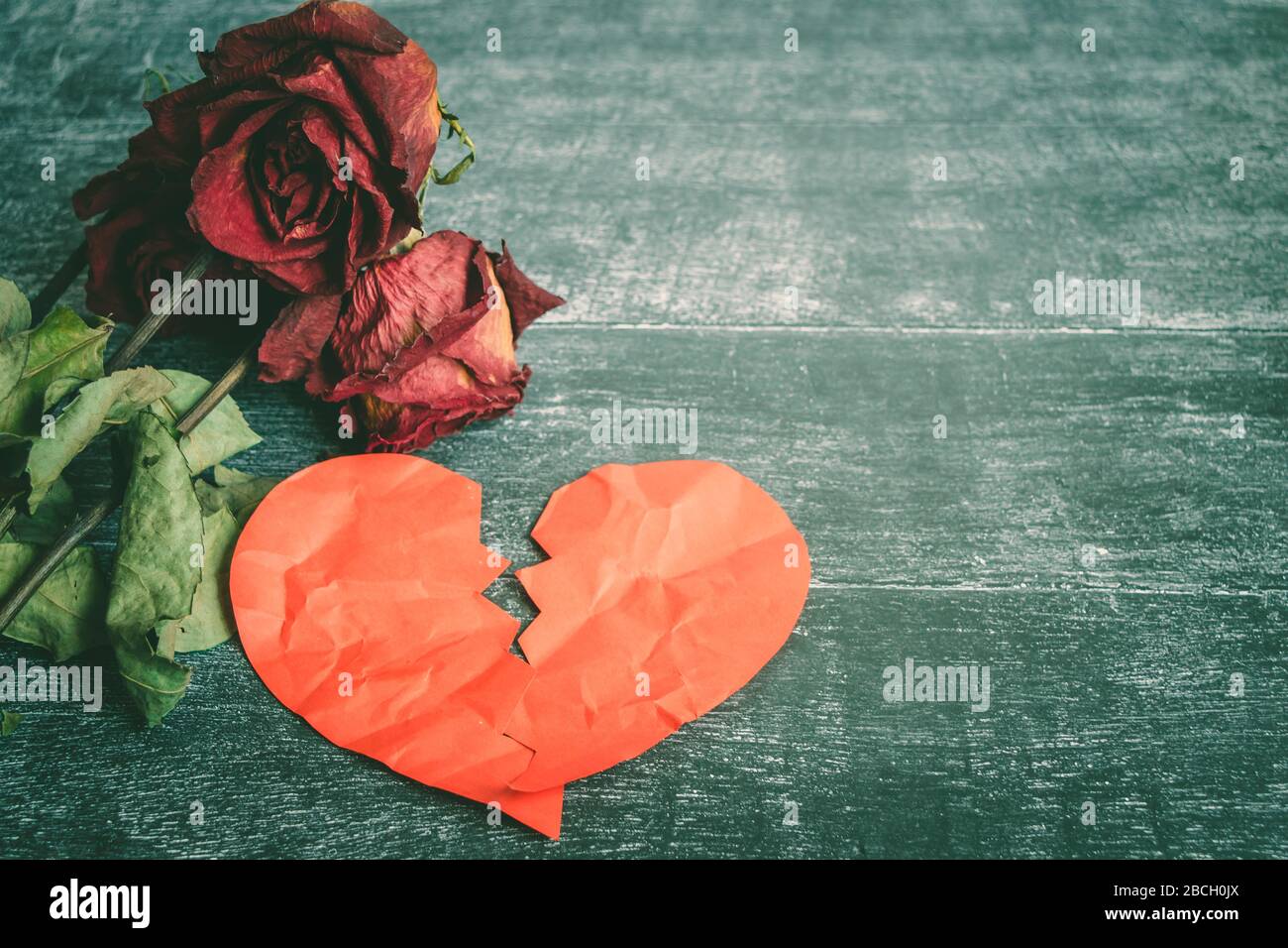Concept de divorce - rouge cœur brisé avec de vieux rose sur fond de bois Banque D'Images