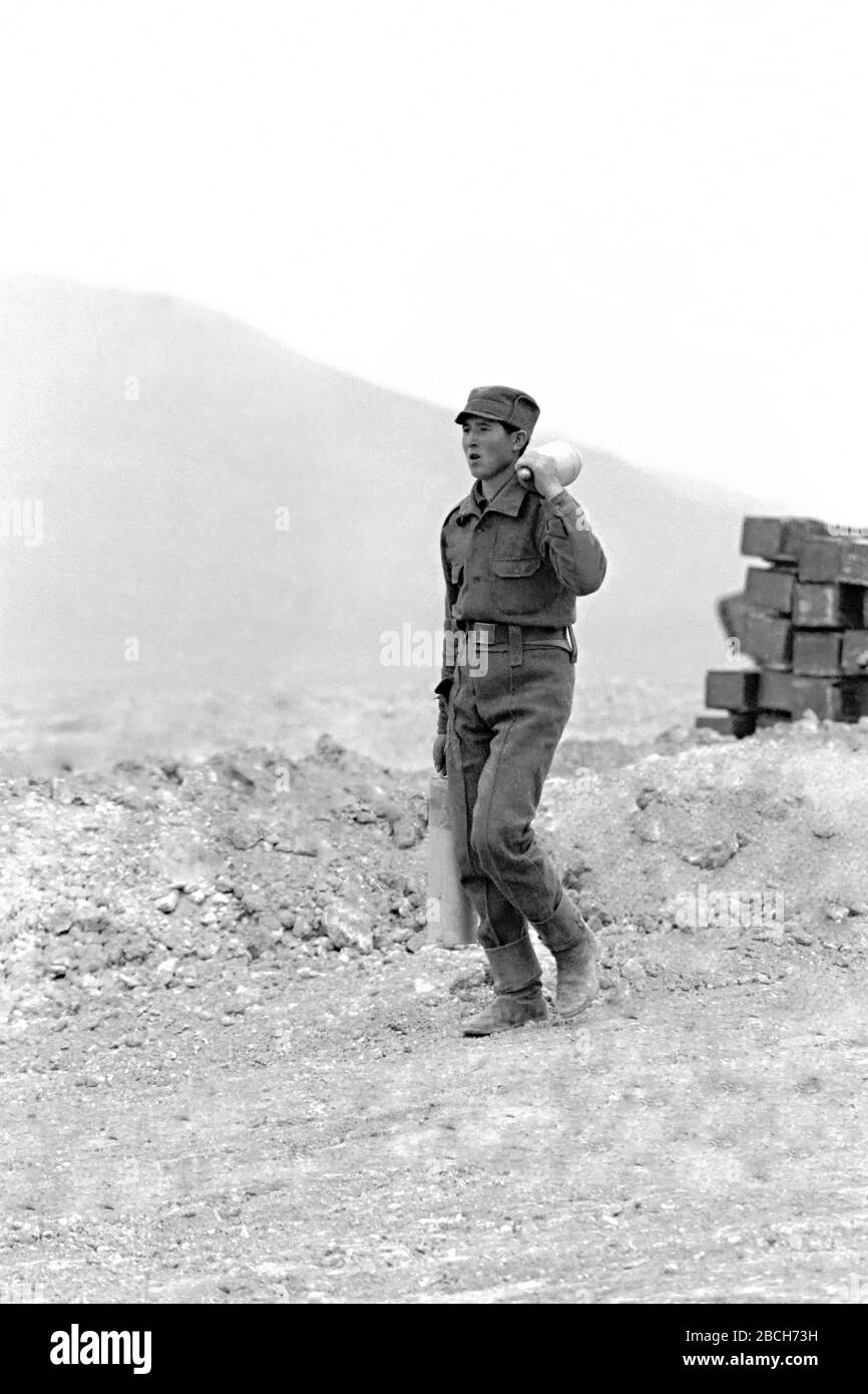 Un soldat afghan porte des tirs d'artillerie pour un canon de 122 mm fabriqué par l'Union soviétique au poste d'opération Pagaman avant le 1er mai 1989 à Pagaman, en Afghanistan. La base protège un point d'entrée principal dans la capitale Kaboul et se trouve à moins d'un kilomètre des lignes de front des combattants afghans mujahidines. Banque D'Images