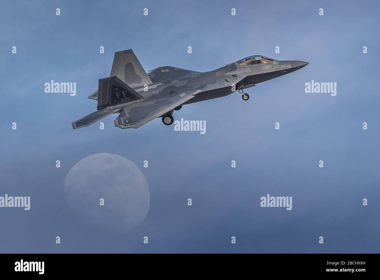 Boeing F-22 A Raptor, de l'armée de l'air des États-Unis, se charge de débarquer sur une lune presque pleine et un ciel bleu. Banque D'Images