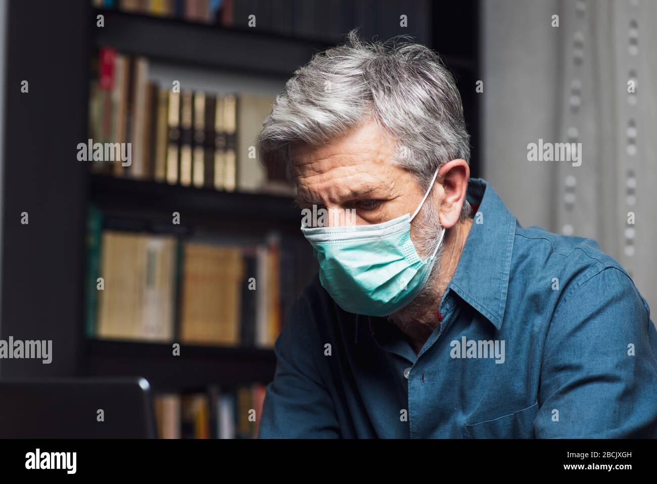 Homme senior portant un masque chirurgical à la maison Banque D'Images