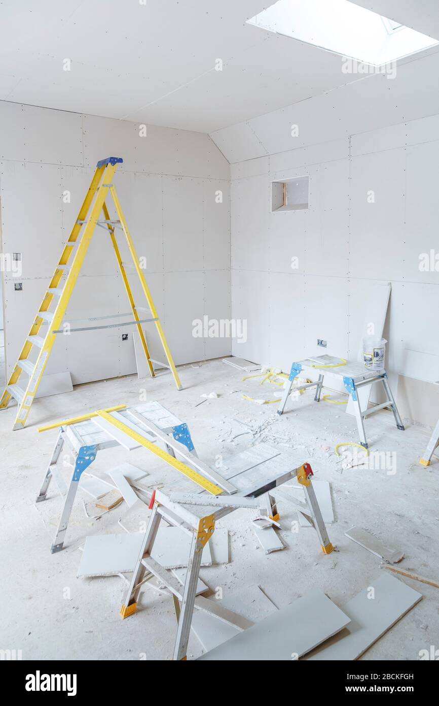 Installation de plaques de plâtre dans un nouvel intérieur de construction avec outils et échelle de pas Banque D'Images