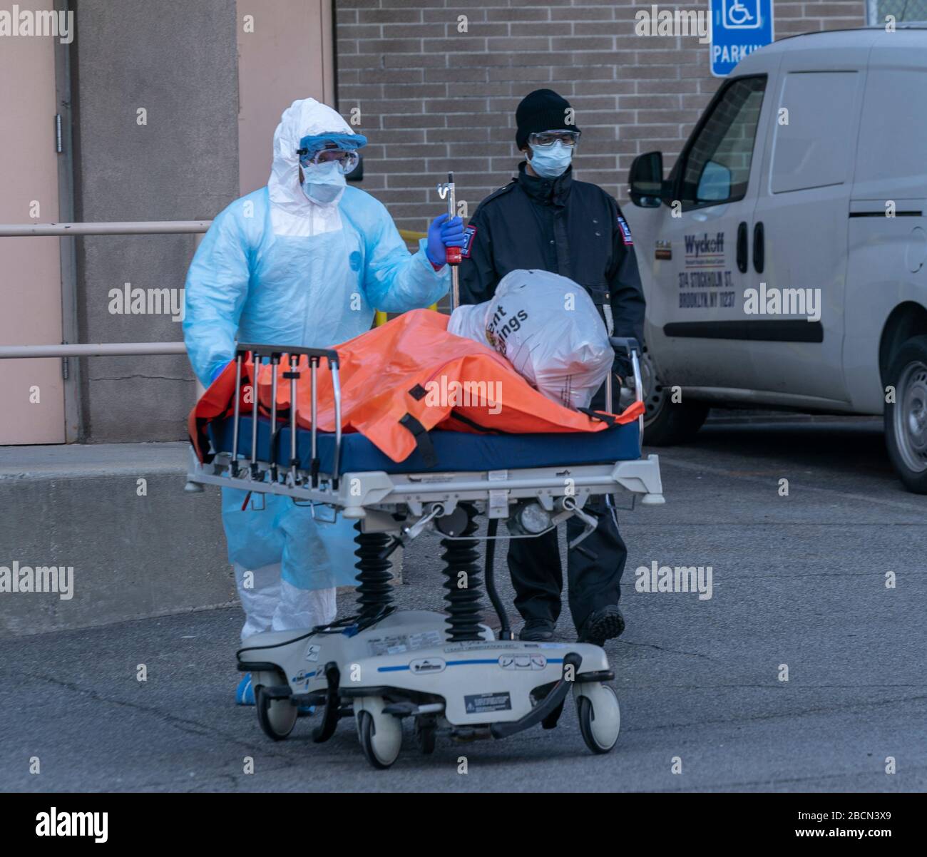 New York, NY - 4 avril 2020 : le corps du patient décédé dans un sac orange est passé de l'hôpital au camion-réfrigérateur servant de morgue temporaire à l'extérieur du centre médical de Wyckoff Heights à Brooklyn Banque D'Images