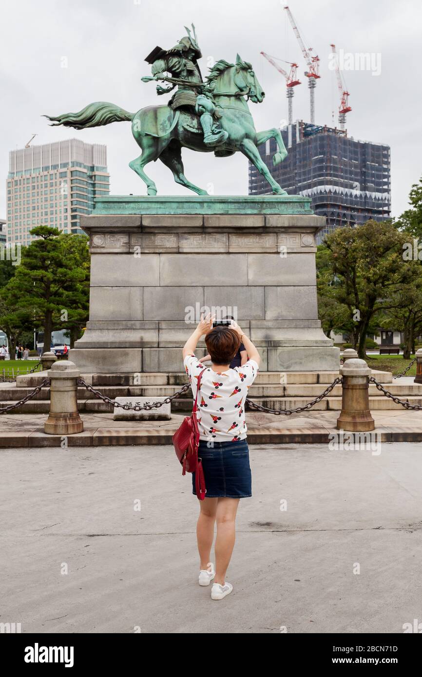 Les touristes chinois prennent des photos devant une statue de samouraï, Kusunoki Masashige dans le jardin est du Palais impérial, Tokyo Japon Banque D'Images