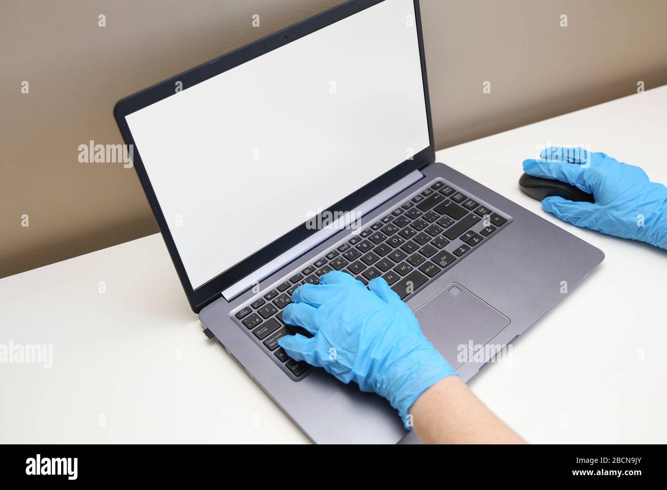 Utilisateur d'ordinateur portant des gants médicaux pour utiliser un ordinateur portable. Banque D'Images