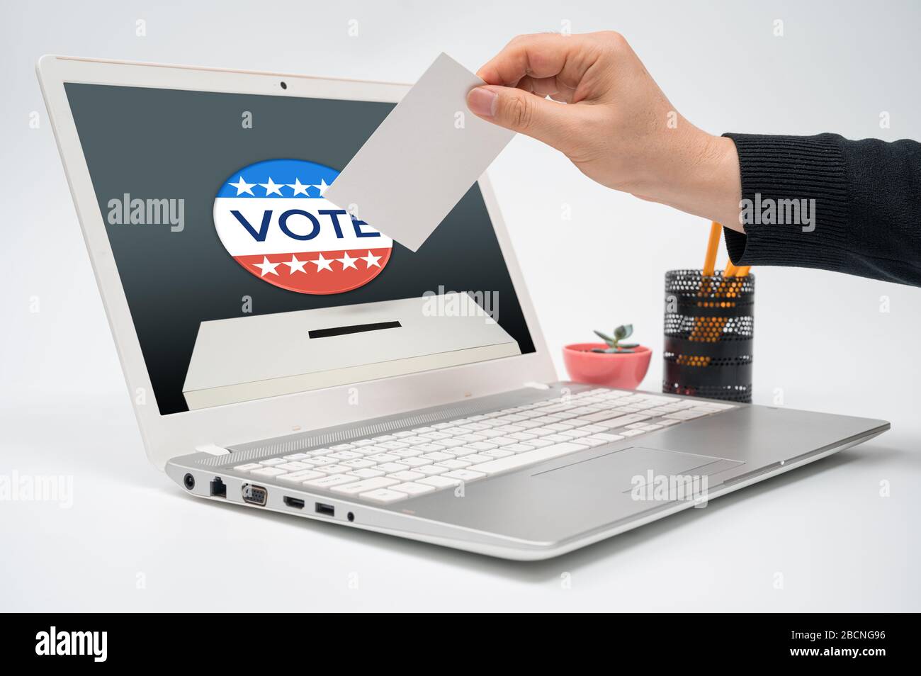 Concept de vote en ligne avec un homme avec un bulletin de vote en main mettant un bulletin de vote vers le moniteur d'ordinateur. Banque D'Images