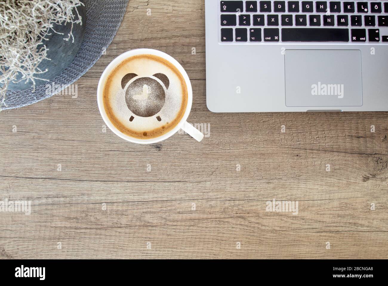 Tasse à café avec icône d'alarme sur une table rustique avec ordinateur portable / bureau à la maison Banque D'Images