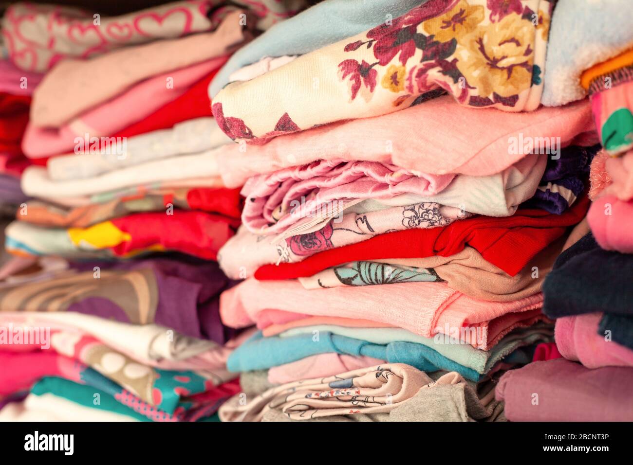 Beaucoup de vêtements pliés colorés pour enfants alignés dans des rangées dans un tiroir, placard. De nombreux vêtements simples pour enfants avec des motifs parfaitement empilés dans une armoire Banque D'Images