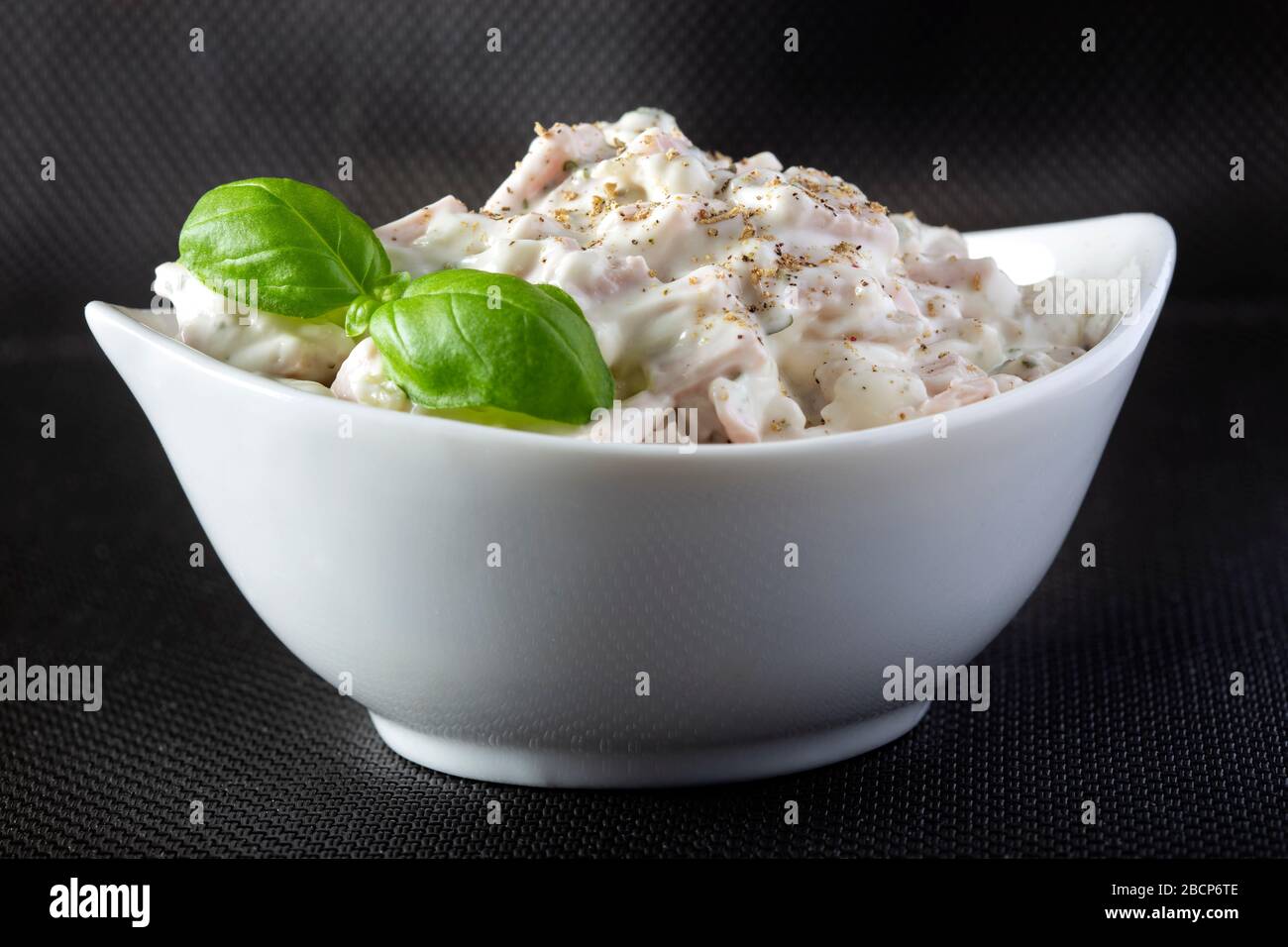 Salade de viande avec mayonnaise et herbes dans un bol blanc Banque D'Images
