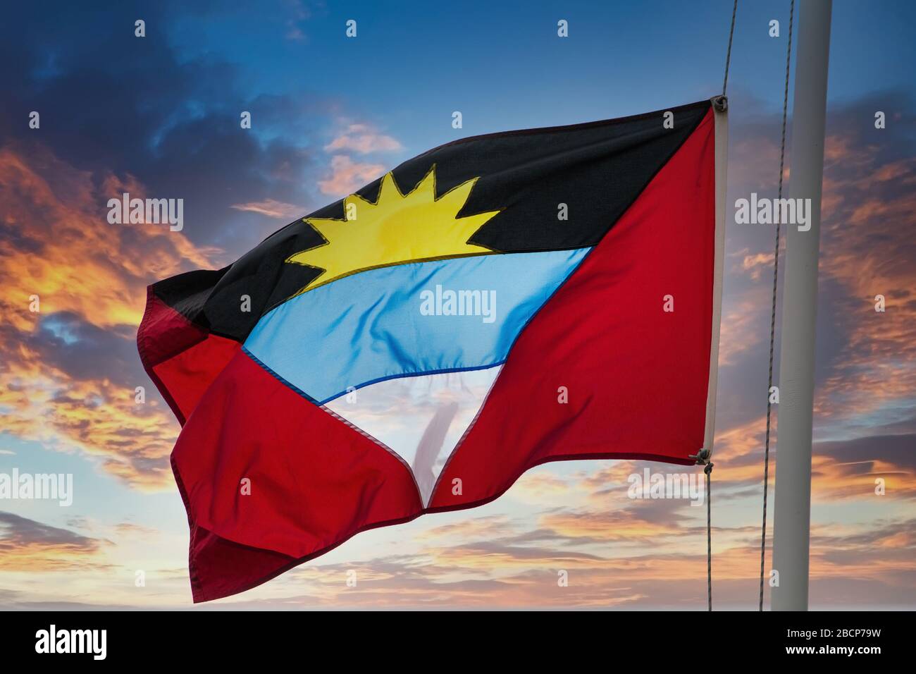Le drapeau d'Antigua agitant dans le vent isolé sur un fond blanc Banque D'Images