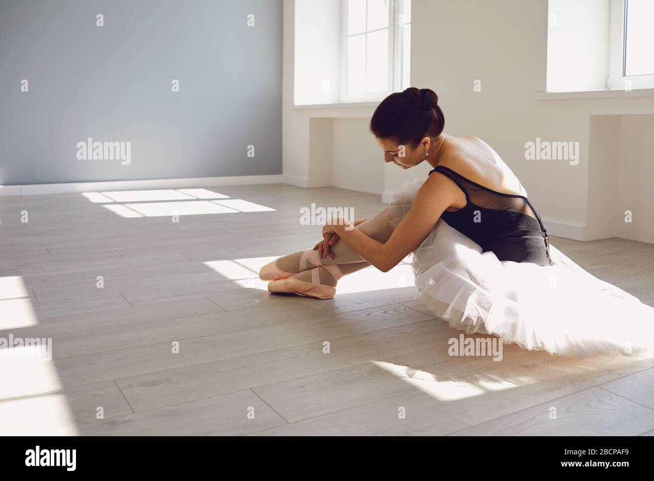 Ballerine de ballet. Jeune fille ballerina robes pointe chaussures assis sur le sol dans le studio. Banque D'Images