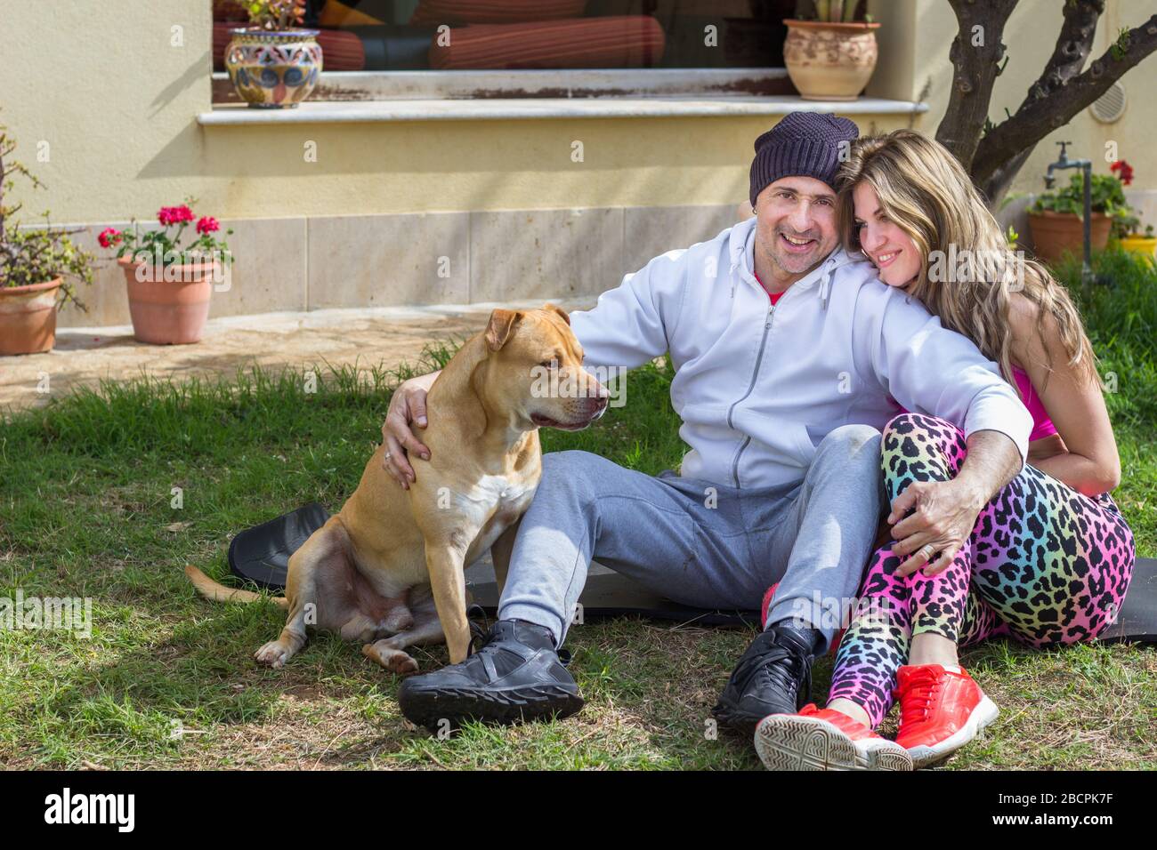Couple jouant avec le chien dans la cour de la maison Banque D'Images