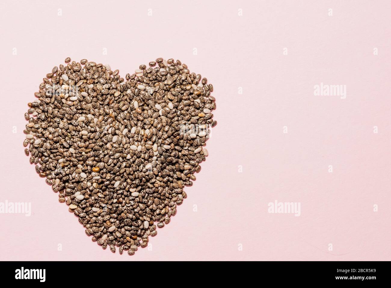 coeur fait de graines de chia sur rose, vie saine et concept de nutrition Banque D'Images