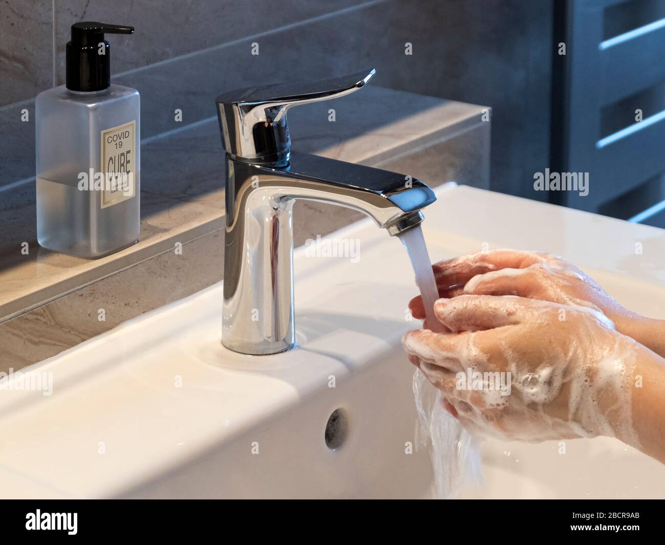 Covid-19 ou Coronavirus avec Cure écrit sur le distributeur de savon pour réduire la contamination des mains de lavage dans le cadre moderne de salle de bains Banque D'Images