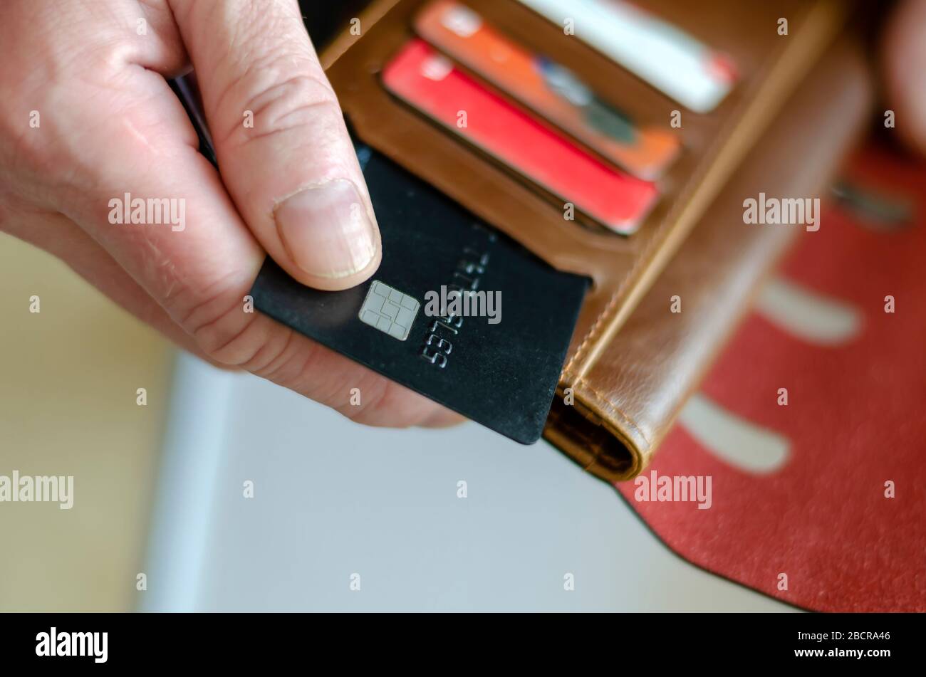 La main sort une carte bancaire du portefeuille. L'homme adulte possède une carte bancaire noire. Paiement des marchandises dans le magasin. Mise au point sélective. Gros plan. Banque D'Images