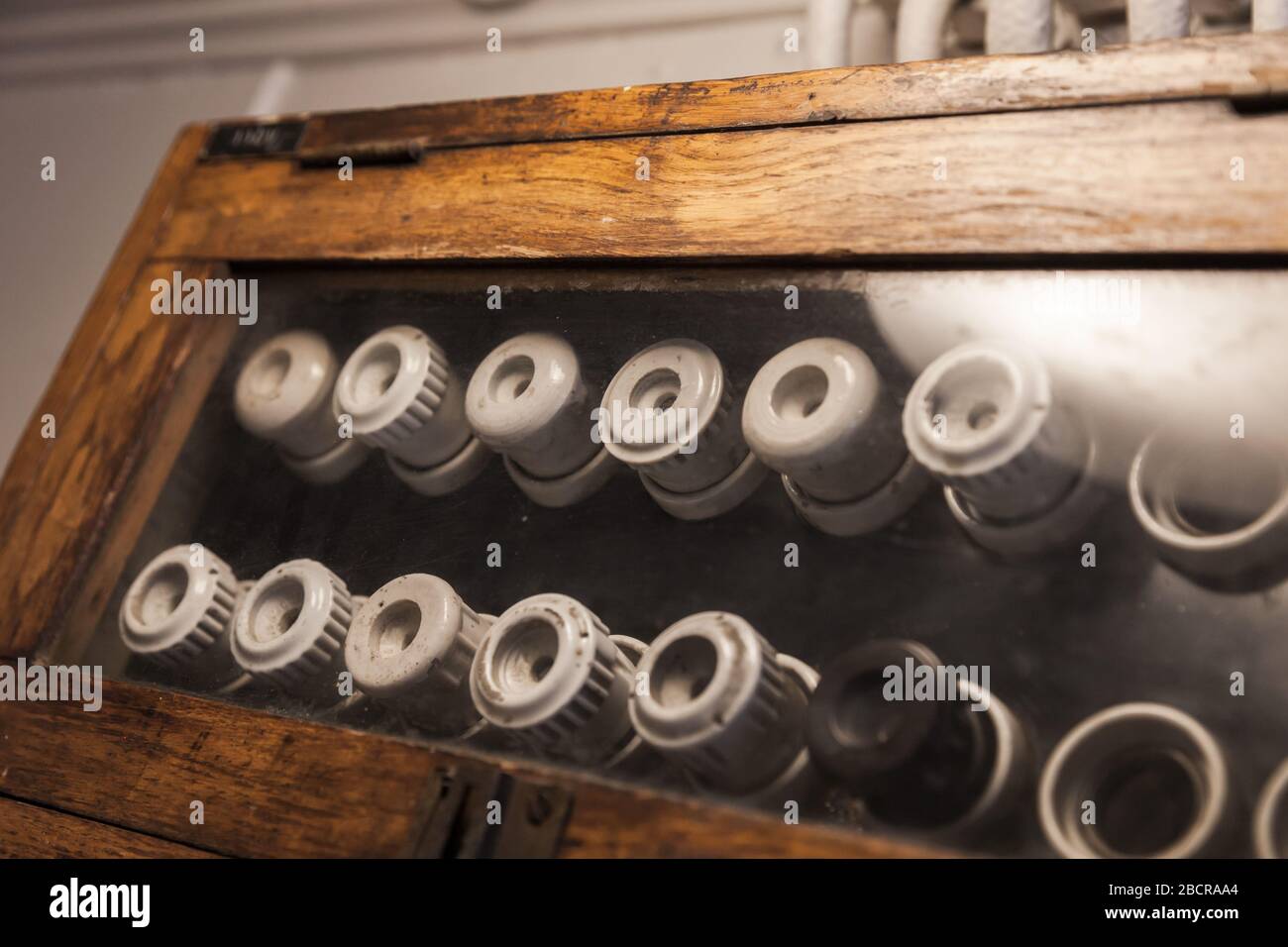 Fusibles électriques anciens montés sur un panneau sombre dans un boîtier en bois Banque D'Images