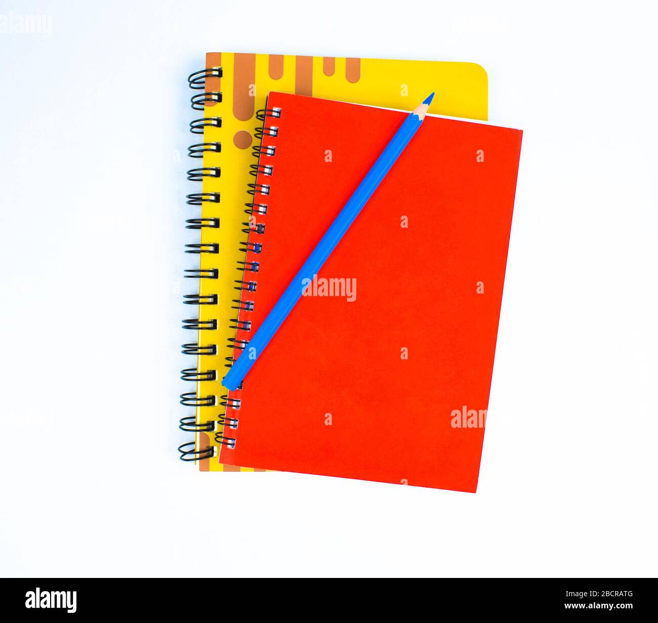 Crayon bleu clair placé sur deux agendas couverts de couleur différente sur un fond blanc Banque D'Images