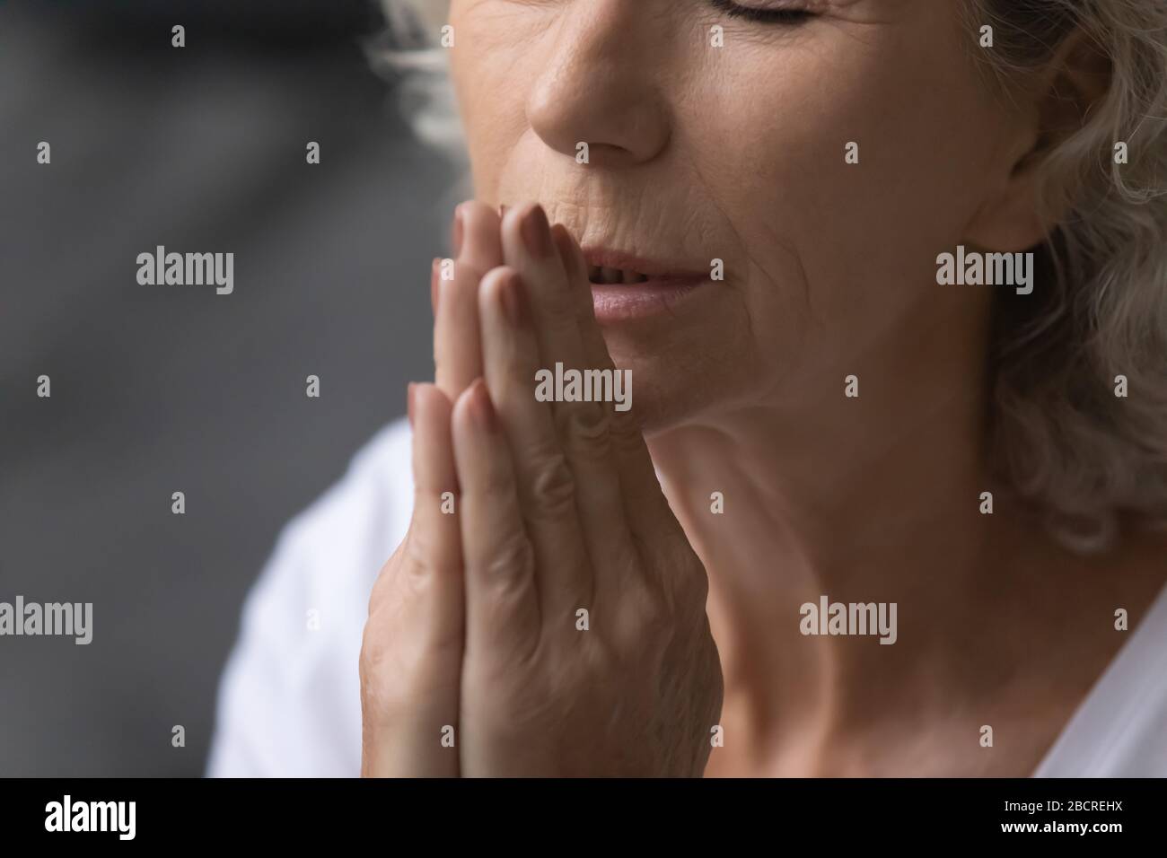 Paisible femme âgée priant dieu avec un geste namaste. Banque D'Images