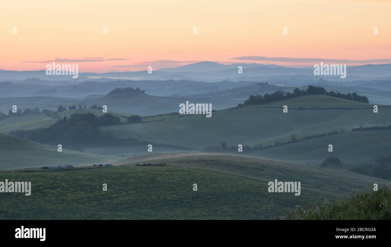 Le lever du soleil brille sur un paysage rural qui roule. Sienne, Italie. Banque D'Images
