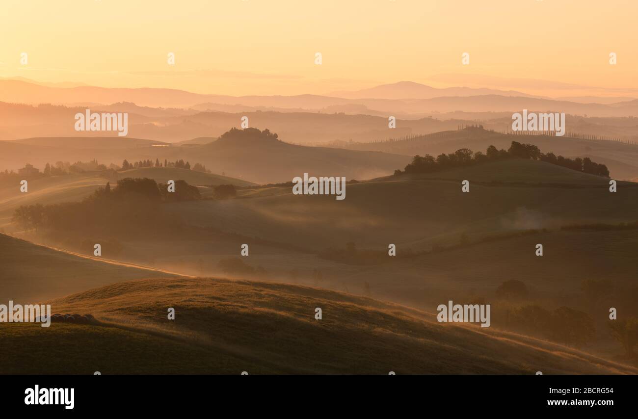 Le lever du soleil brille sur un paysage rural qui roule. Sienne, Italie. Banque D'Images