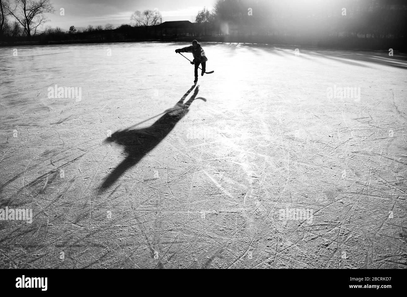 Silhouette d'un jeune joueur de hockey qui s'amuse sur la glace naturelle. Original, sport, papier peint d'hiver Banque D'Images