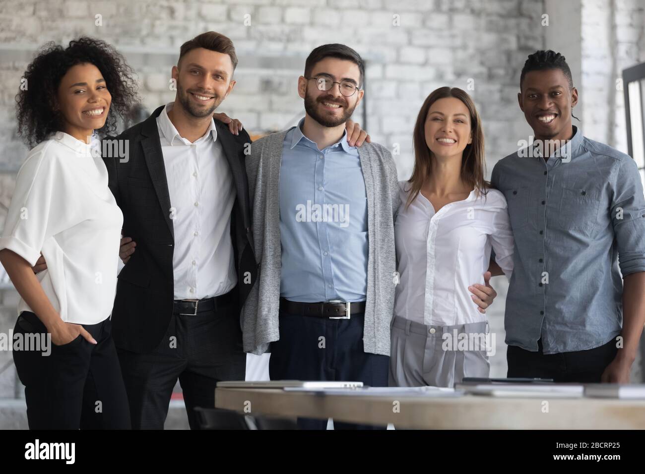 Portrait d'une équipe multiraciale en rangée souriante embrassant. Banque D'Images
