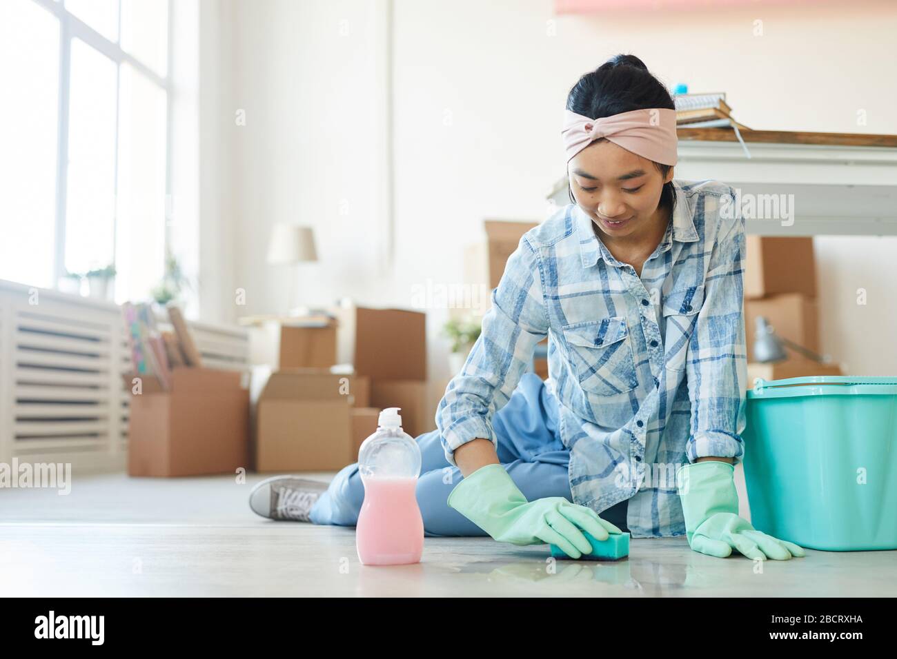 Portrait complet d'une heureuse femme asiatique nettoyer le sol dans une nouvelle maison ou un appartement après avoir bougez, copier l'espace Banque D'Images