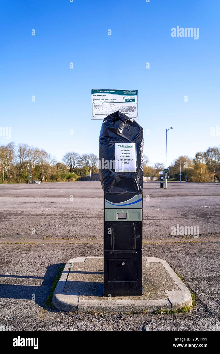 Un ticket de parking public couvert d'un sac poubelle et une affiche indiquant les frais de stationnement suspendus en cas d'urgence à Coronavirus Banque D'Images