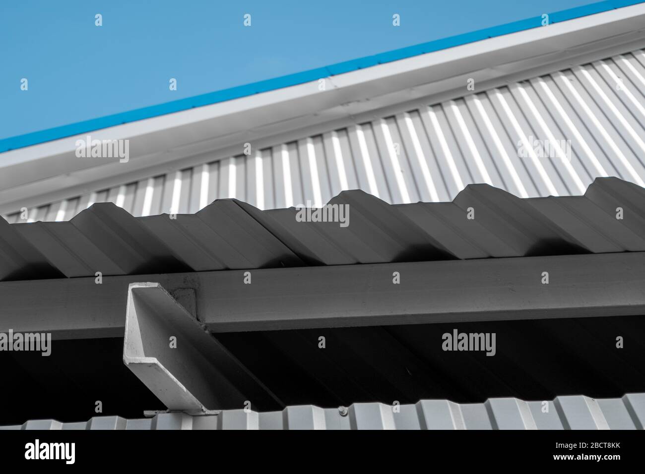 Surface de tôle ondulée blanche du mur et du coin métallique du toit. Arrière-plan en acier galvanisé. Banque D'Images