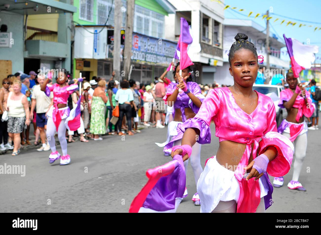 Carnaval en Dominique. Groupe de jeunes filles en costumes roses dansant en spectacle de carnaval. Banque D'Images