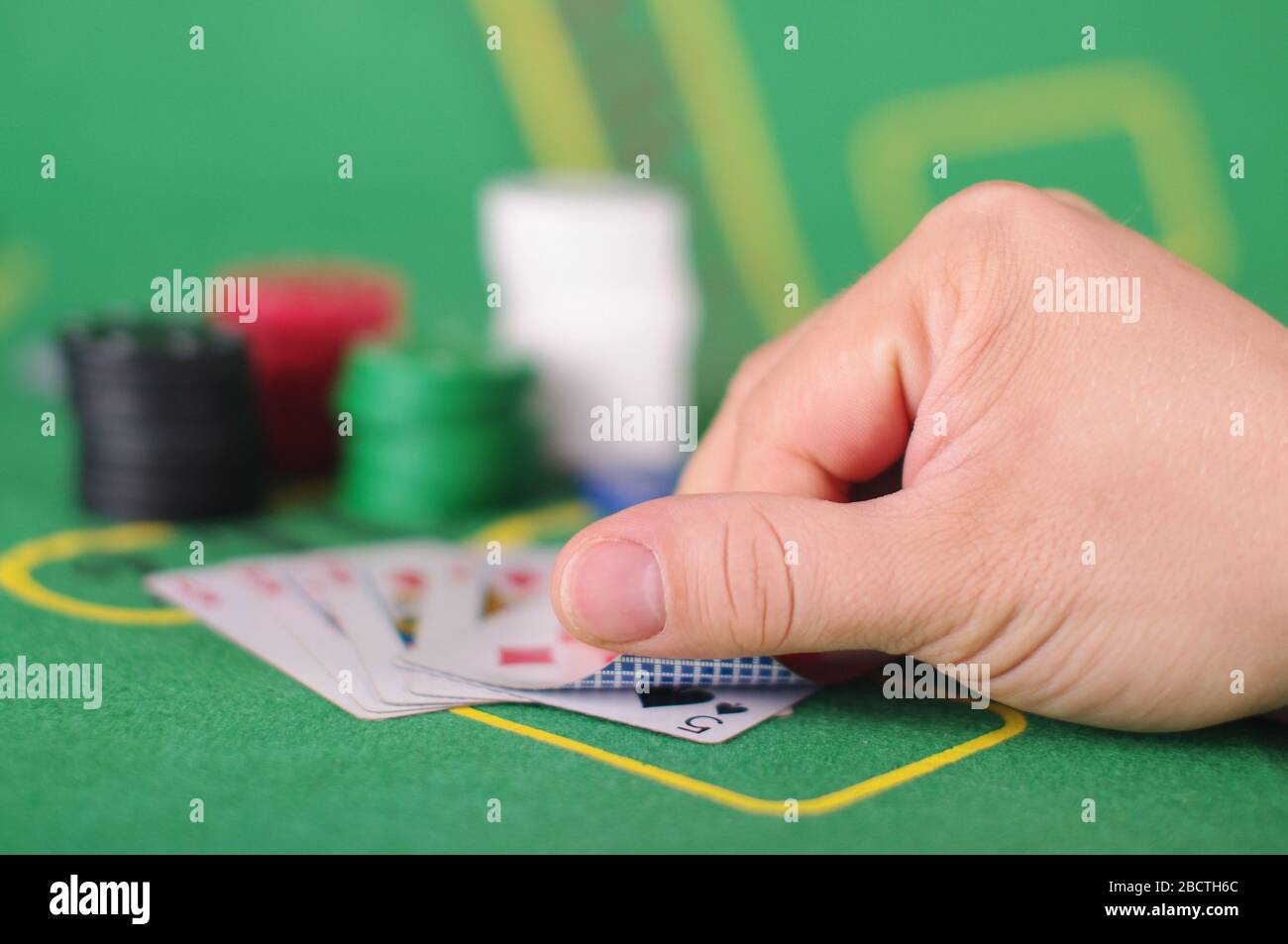 Main mâle tenant des cartes de poker sur le tapis de poker vert et les  accessoires Photo Stock - Alamy
