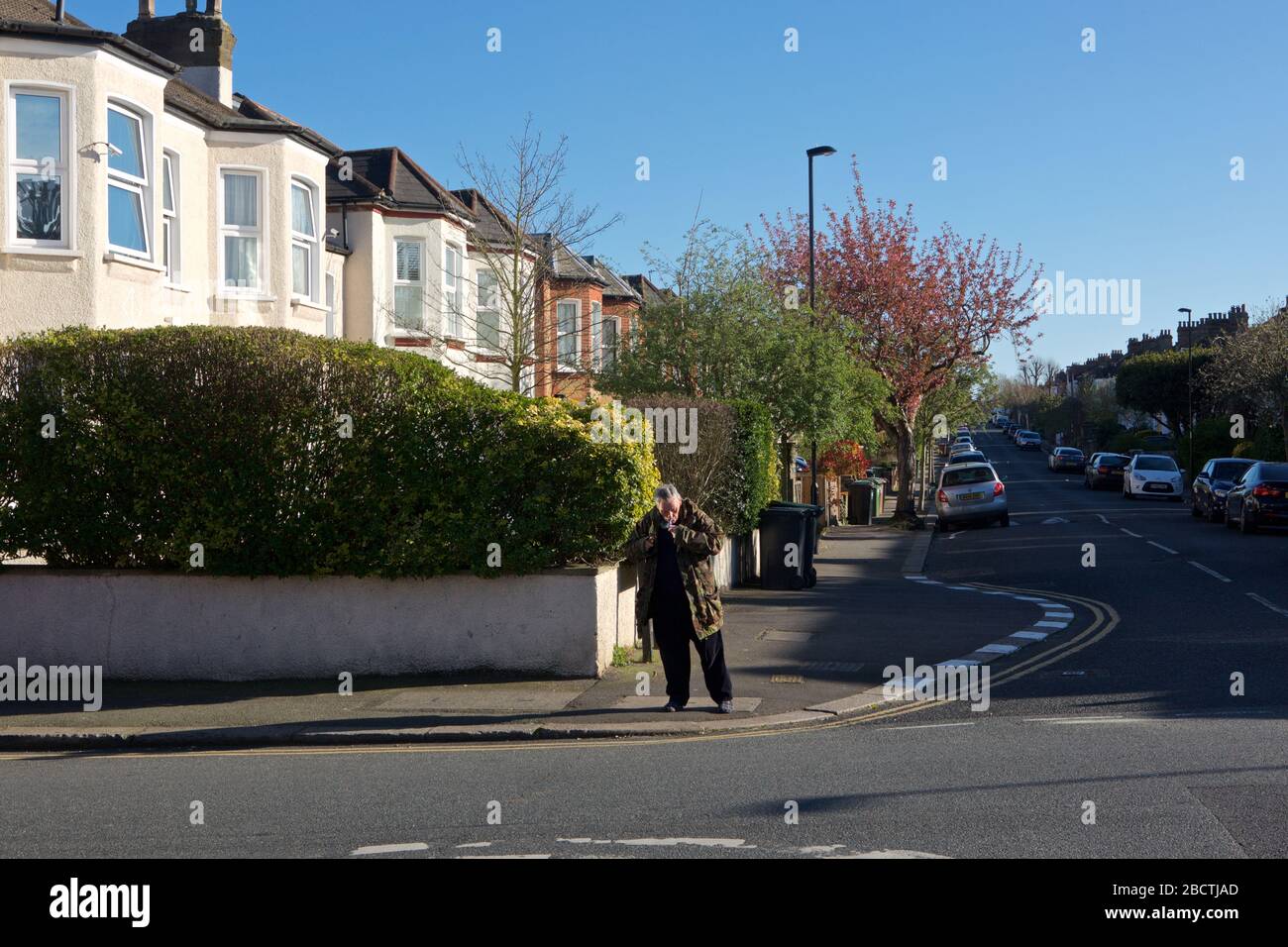 Londres, Royaume-Uni. Coronavirus. Un homme semble fumer ouvertement de crack cocaïne au coin des rues résidentielles, principalement désolées, pendant le covid- 19 Banque D'Images