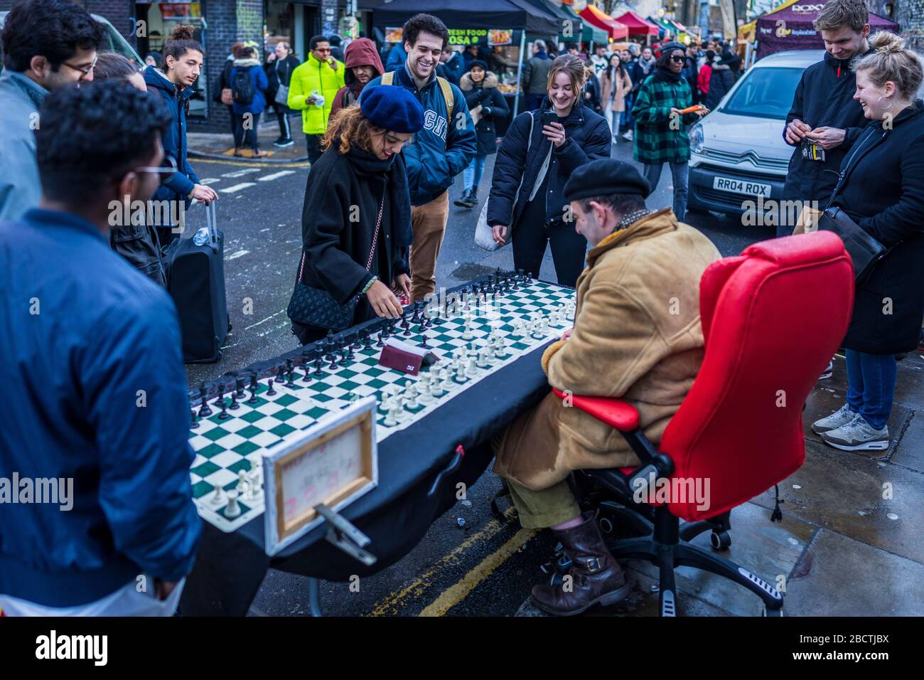 London Street Chess - un joueur d'échecs joue jusqu'à 4 matches simultanés avec les touristes et les passants dans le célèbre marché du dimanche Brick Lane de Londres Banque D'Images