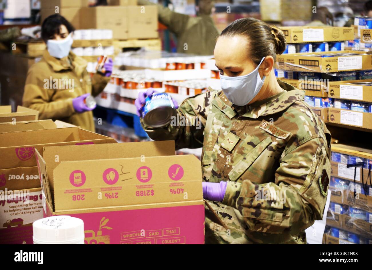 U.S. Air Force Airman 1ère classe Alicia Day, emballe une boîte avec de la nourriture en conserve à la Food Bank pour aider avec COVID-19, soulagement du coronavirus 3 avril 2020 à Lakewood, Washington. Banque D'Images