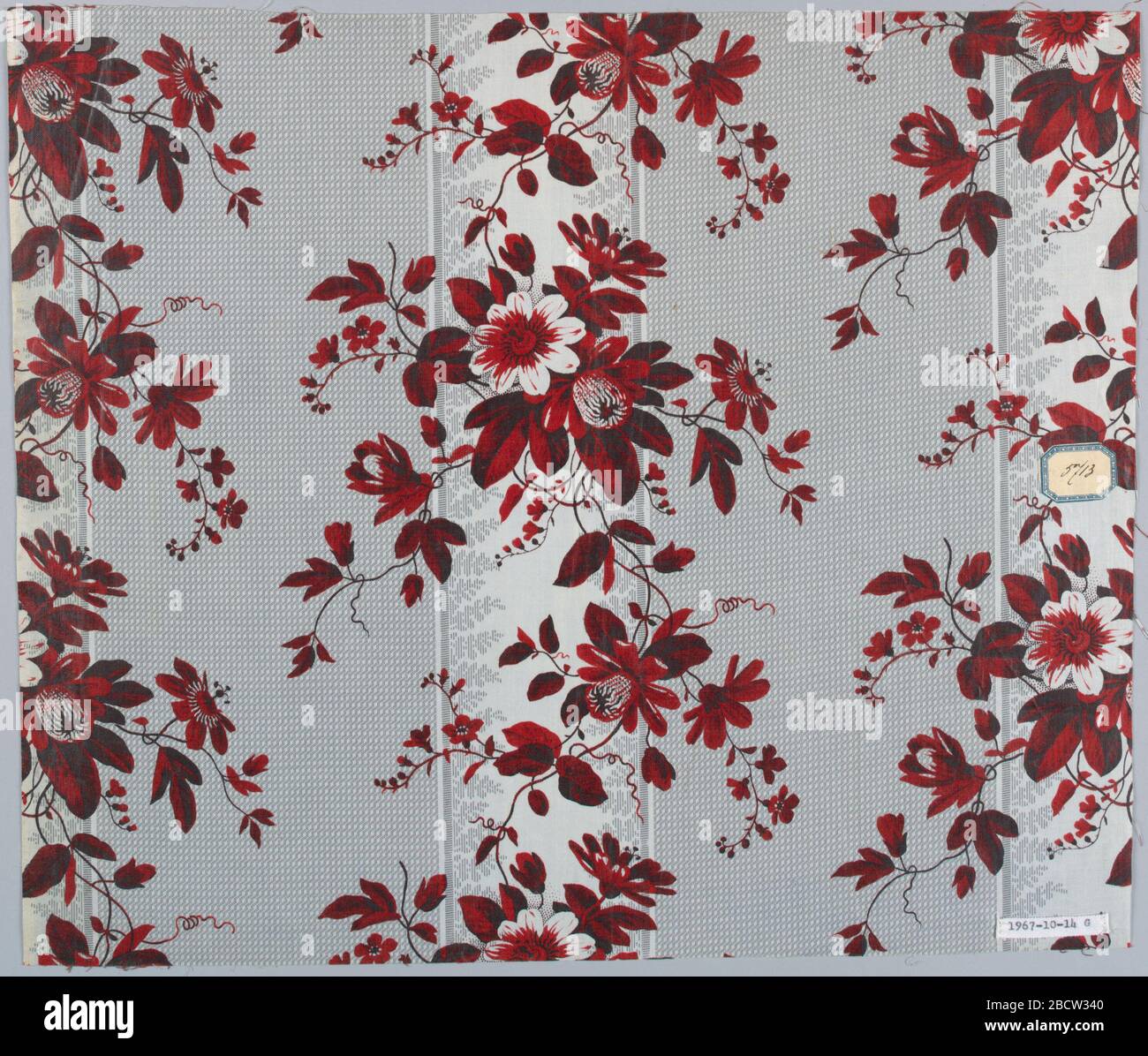 Textile. Recherche dans ProgressGroup ayant le même sol, imprimé à rouleaux, d'une large bande grise formée de points blancs minute alternant avec une bande blanche bordée de feuilles fantaisie. Motifs floraux différents imprimés sur ce sol, probablement par bloc. Textile Banque D'Images