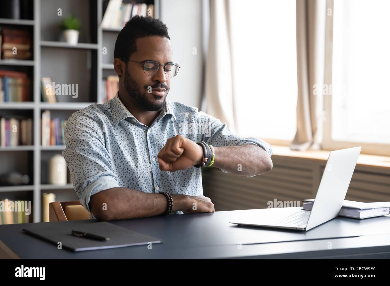 Un employé africain américain de sexe masculin vérifie son temps au travail Banque D'Images