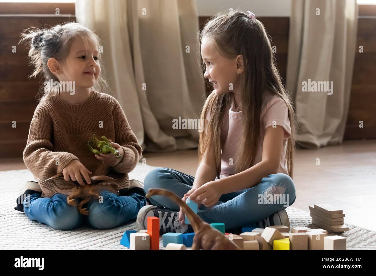 Adorables petites sœurs pour enfants jouant avec des jouets dans le salon. Banque D'Images