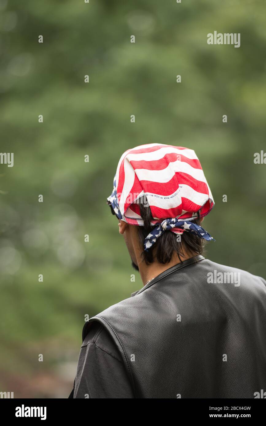 Derrière un homme portant une veste en cuir noir et un bandana drapeau américain couvrant sa tête lors d'un événement du 4 juillet. Banque D'Images