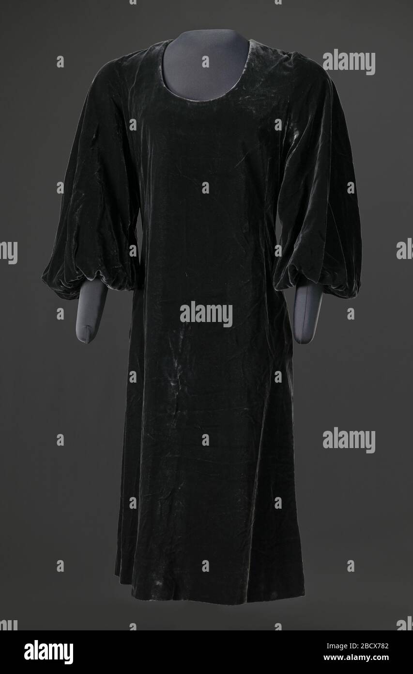 Robe en velours gris foncé conçue par Arthur McGee. Robe en velours gris foncé conçue par Arthur McGee avec décolleté rond, manches longues et corps EN A avec ourlet juste au-dessous du genou. Il y a deux (2) poches encastrées cousues dans les coutures latérales de chaque hanche. La robe se ferme au centre du dos avec une fermeture éclair. Robe en velours gris foncé conçue par Arthur McGee Banque D'Images