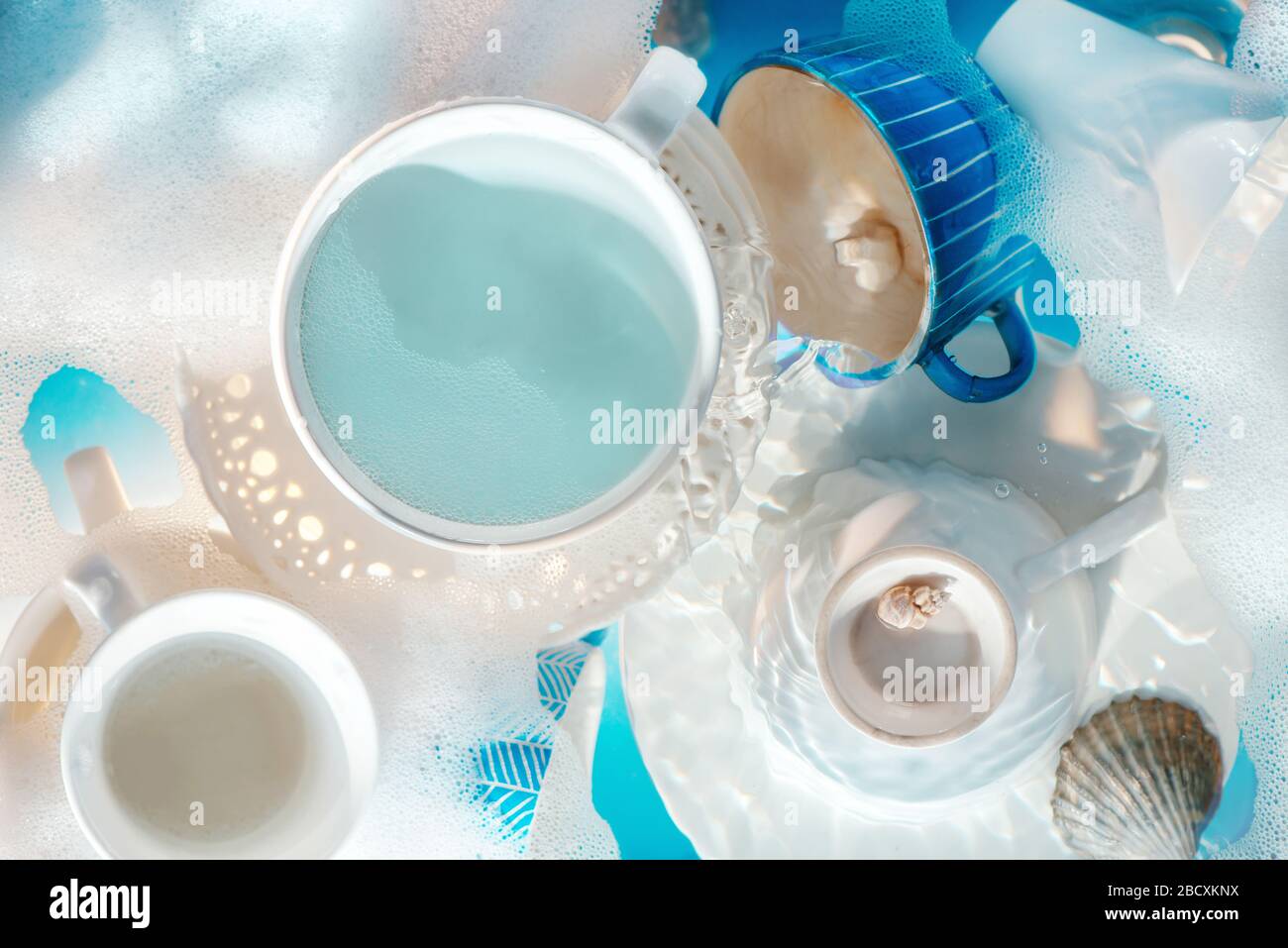 Concept de vaisselle, assiettes et tasses en porcelaine blanche avec bulles et mousse Banque D'Images