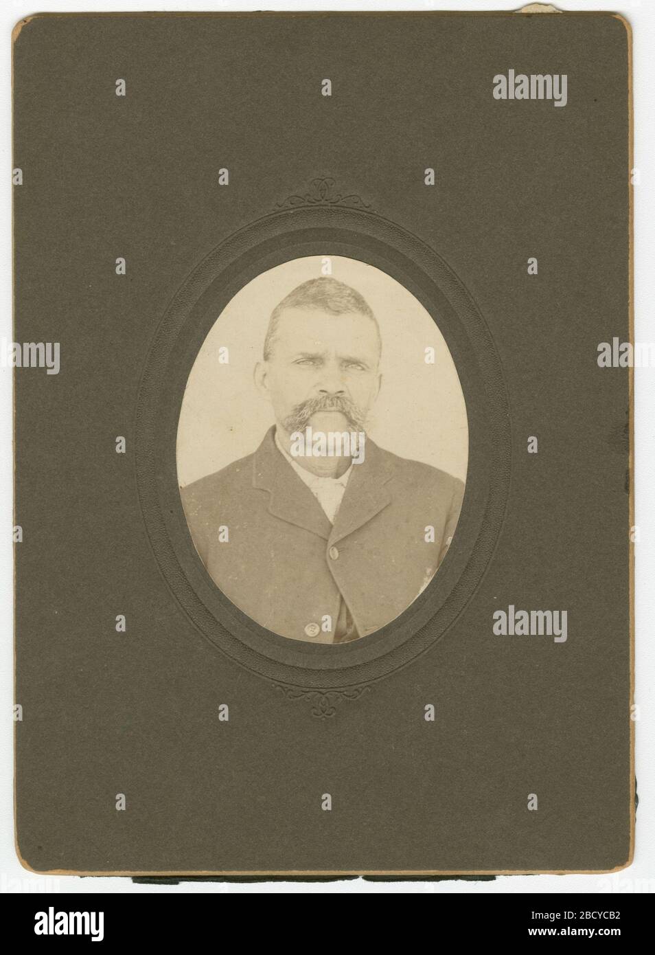 Photographie d'un homme avec une moustache portant une veste sombre. Portrait d'un homme portant une veste de couleur sombre et une chemise légère sur une carte d'armoire noir et blanc. Le bouton supérieur de la veste est boutonné et il a une moustache. La photo ovale est sur le cartstock noir. Il n'y a pas d'inscriptions à l'avant ou à l'arrière. 2014.61.13 Banque D'Images