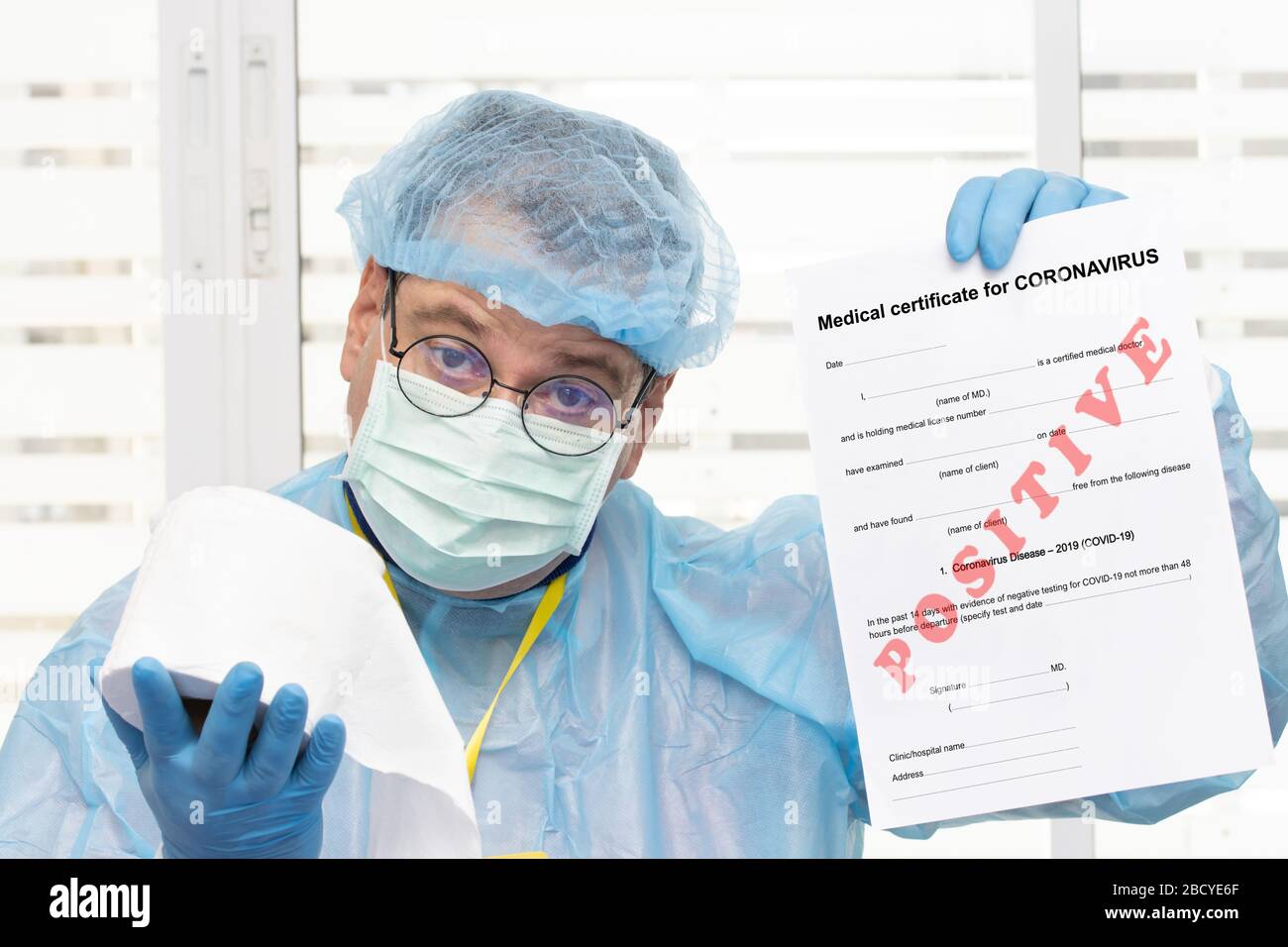 Médecin en costume de protection portant un certificat médical positif au coronavirus - covid 19 et offre du papier toilette. L'examen de laboratoire du sang Banque D'Images