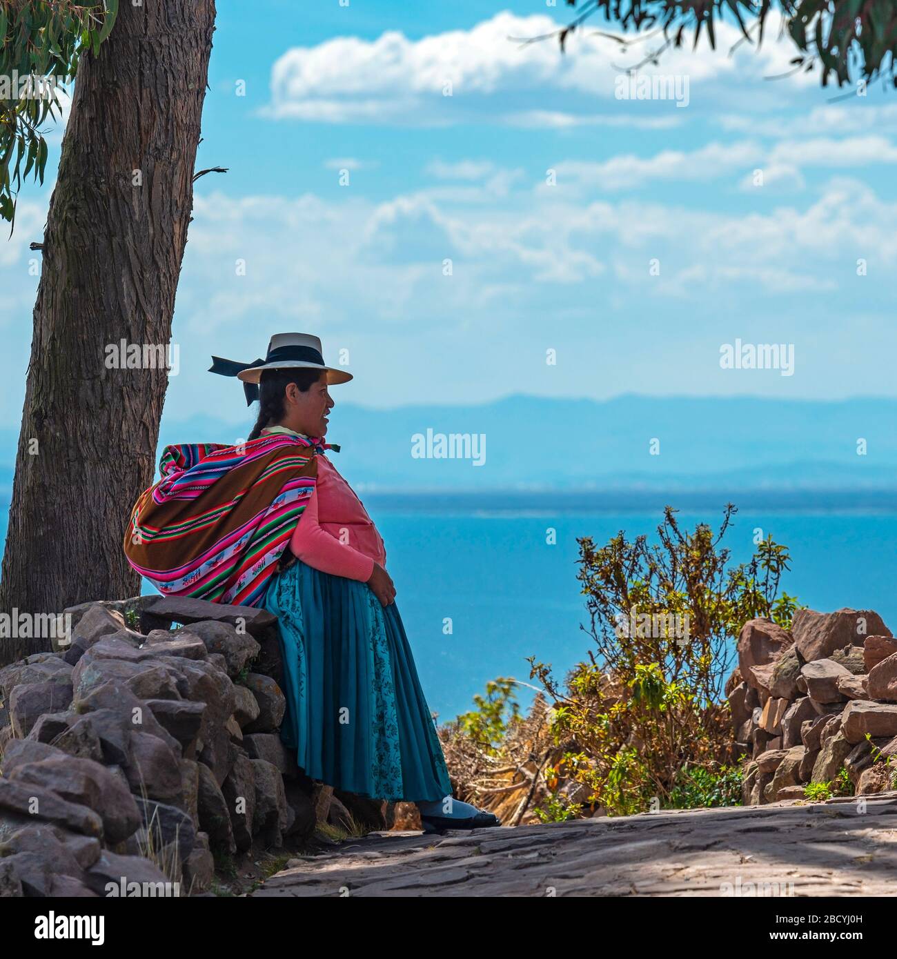 Femme indigène péruvienne quechua dans les vêtements traditionnels avec le lac Titicaca en arrière-plan, Isla Taquile, Pérou. Banque D'Images