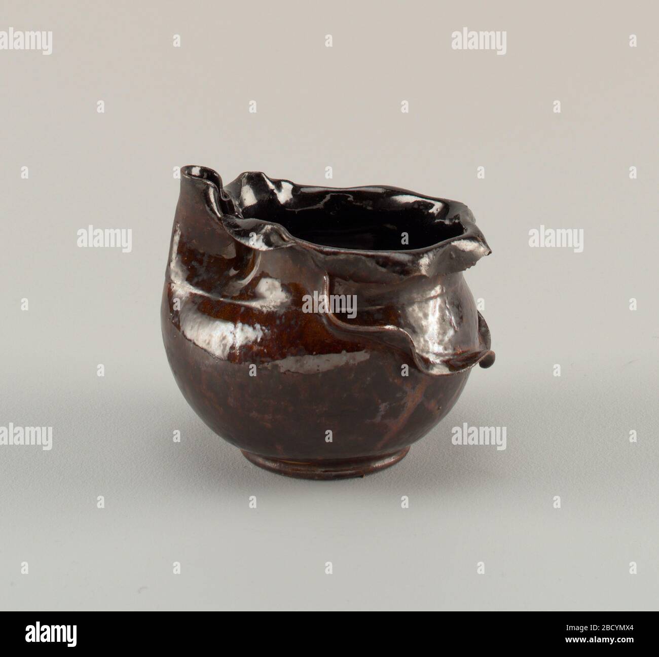 Vase. Recherche en ProgressVase avec bec. Corps en argile de couleur rouge-buff, jeté. Corps globulaire avec bec vertical replié, ligne incisée démarque l'épaule, bord plat en forme de ruffé tourné vers le bas avec bords dentelés ; pied plat bas. Vase Banque D'Images