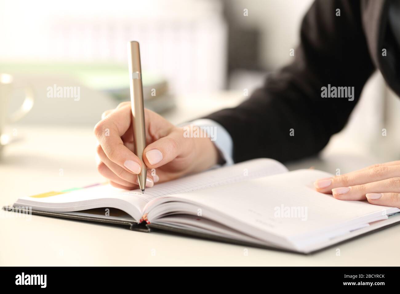 Gros plan sur les mains de la femme exécutive écrivant des notes à l'ordre du jour au bureau Banque D'Images