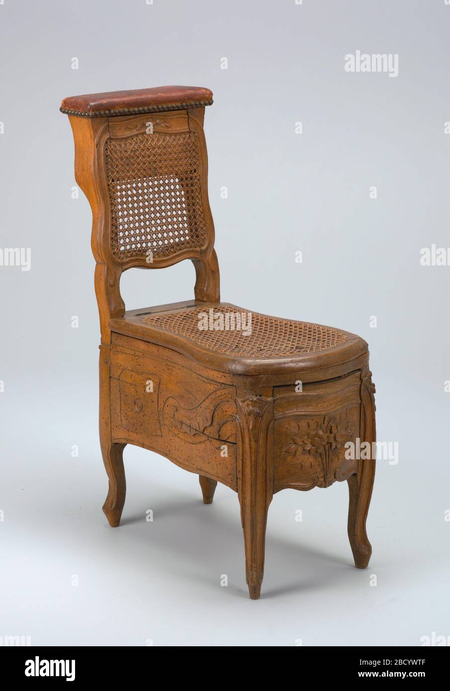 Chaise commode. A) bidet en bois sculpté avec dos fourré, quatre pieds cabrioles, dos avec ornement rocaille au pied, avant avec petits rouleaux au pied; couvercle à charnière recouvert de cuir au-dessus du support arrière dissimulant trois compartiments. Chaise commode Banque D'Images
