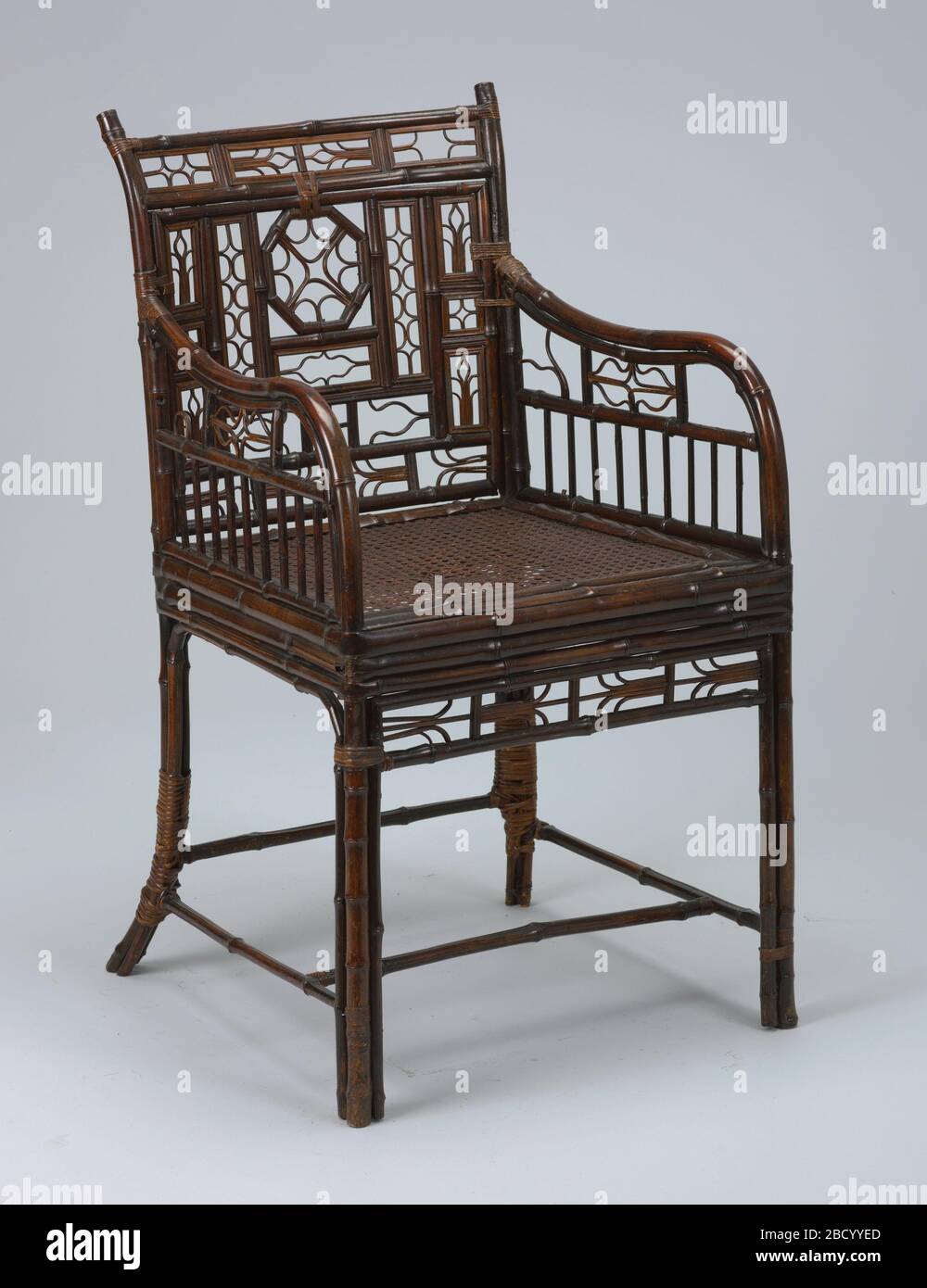 Fauteuil d'exportation chinois. Recherche en ProgressArmchair, place en plan, entièrement construite en bambou, sauf pour le siège cané. Dos conçu avec de petites ouvertures rectangulaires, chacune avec un petit motif ouvert. Détails similaires travaillés sous l'accoudoir et le long du rail avant. Brun foncé verni. Fauteuil d'exportation chinois Banque D'Images