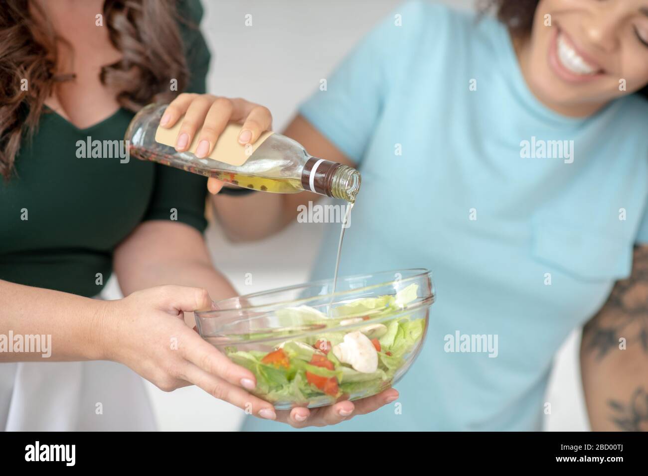 Mains de deux femmes assaisonnement alimentation salade de légumes. Banque D'Images